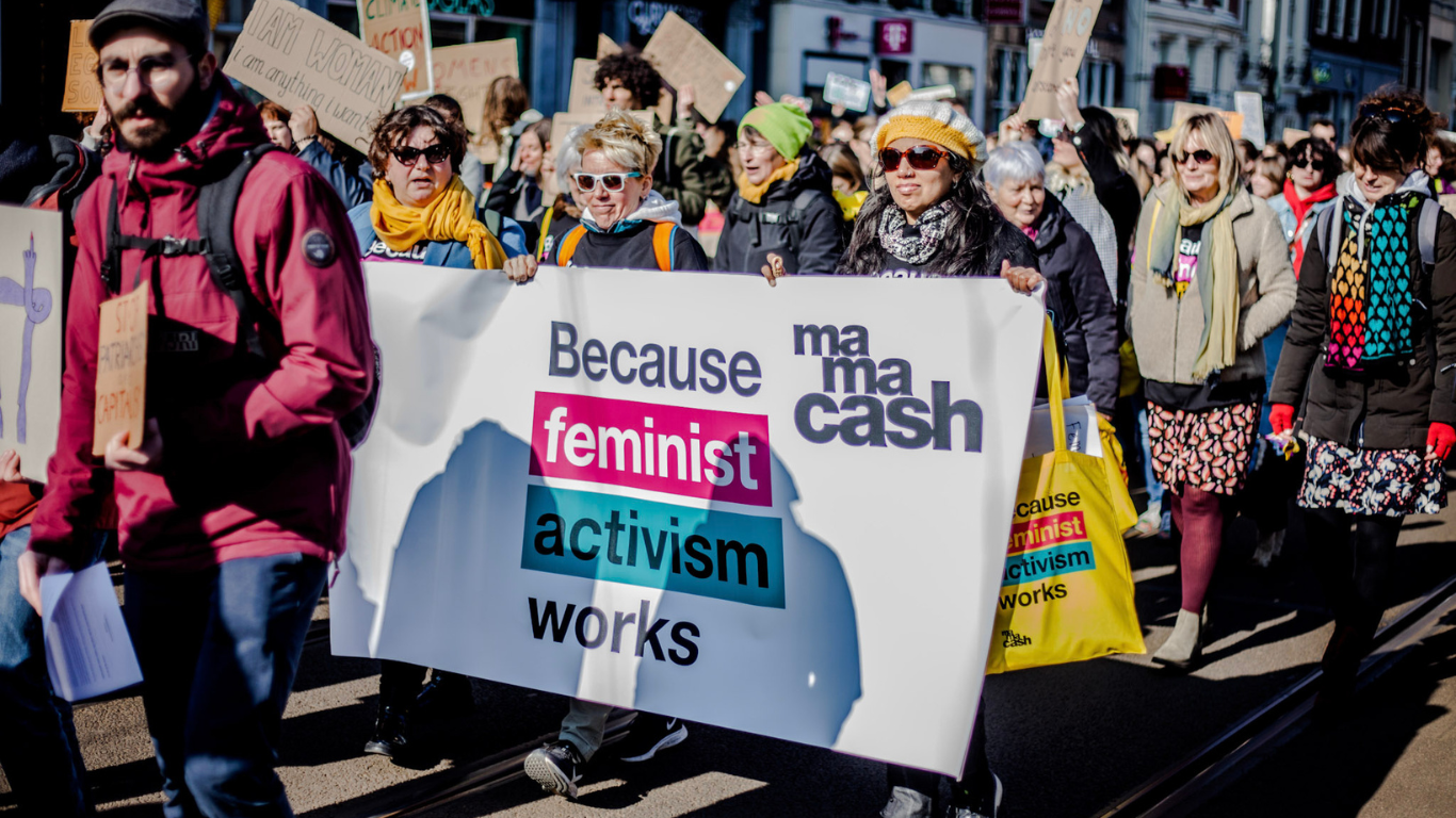 Activists marching with Mama Cash Banner reading: Because Feminist Activism Works